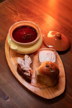 Restaurant dish borscht, delicious bread with bacon, sour cream, bun. A delicious photo for a menu, culinary website, or an advertisement for catering establishments