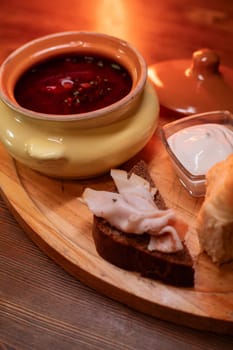 Restaurant dish borscht, delicious bread with bacon, sour cream, bun. A delicious photo for a menu, culinary website, or an advertisement for catering establishments