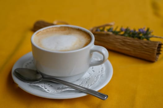 A frothy coffee invitation rests on a cheerful yellow tablecloth with playful decorative touches.