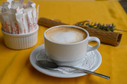 The rich aroma of coffee fills the air, warming the cup against the lively yellow fabric below.