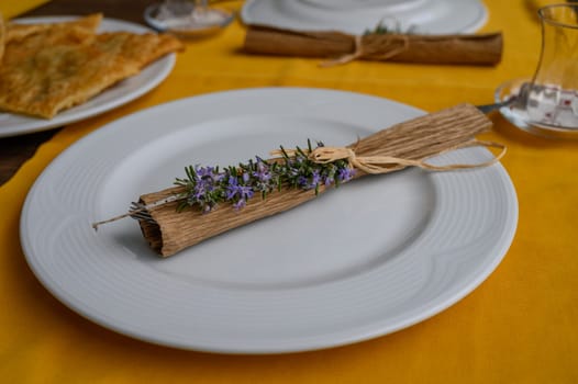 A skillfully arranged dish features fresh herbs atop a rolled leaf, set on a vibrant yellow tablecloth.
