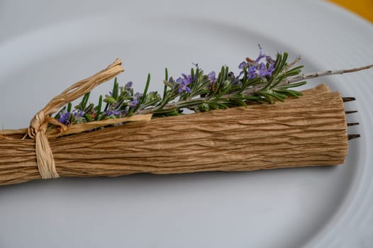 Rustic dining setting showcases beautiful herbs and flowers artistically arranged on a plate, highlighting elegance.