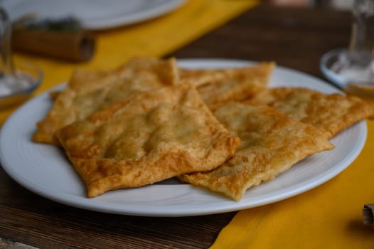 Golden pastries resting on a white dish, inviting diners to savor a crispy, flaky delight during a casual gathering.