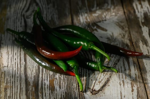 A colorful mix of green and red chili peppers on a weathered wooden surface adds a rustic touch.