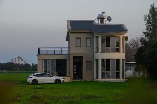 Stylish residence stands gracefully amidst vibrant grass as evening light casts a serene glow over the landscape.