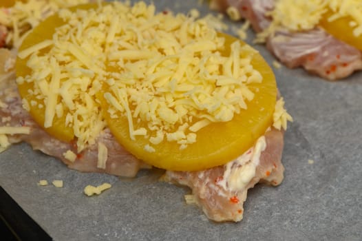 Juicy chicken breasts are layered with pineapple slices and a generous amount of cheese, prepped for baking.