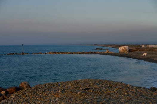 Calm waters reflect the soft hues of dusk while pebbles border the tranquil shoreline of this beautiful coast.