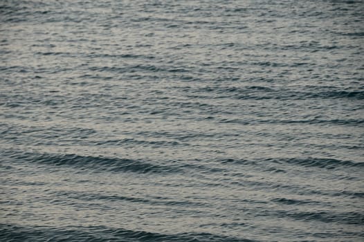 Soft waves ripple gently along the beach as twilight casts a serene glow over the ocean.