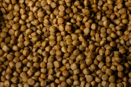 Brown pet food pellets are tightly packed together, revealing their unique shapes and textures in natural light.