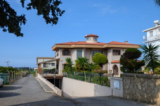 A charming villa stands proudly amidst vibrant foliage, exuding elegance in a peaceful neighborhood by the sea.