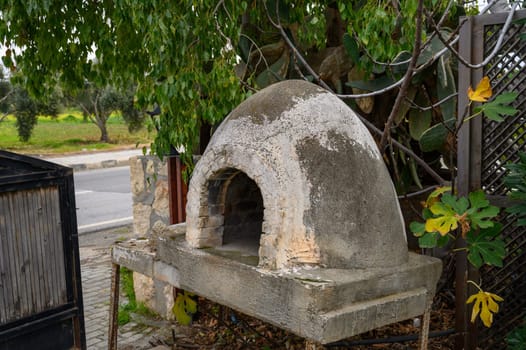 Rustic stone oven sits peacefully among lush foliage, blending with nature on a serene afternoon in the countryside.