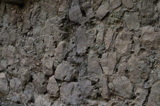 Ancient stones form a rugged wall, showing texture and history under soft light in a serene environment.