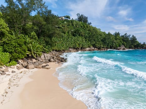 The gentle surf of the turquoise ocean meets the sandy beach. Seychelles, Mahe. Anse Intendance beach.