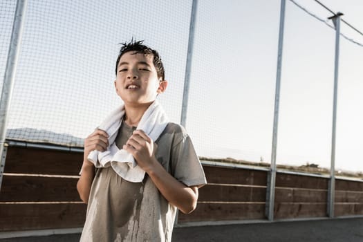 A confident boy with a towel around his neck after a hard practice looks ready for more.