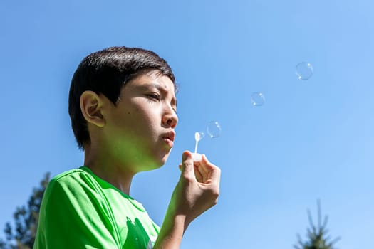 A young boy blowing bubbles with a toy.