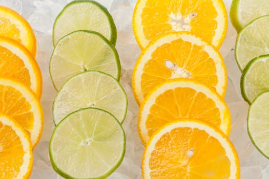 Rows of orange and lime slices laying on ice.