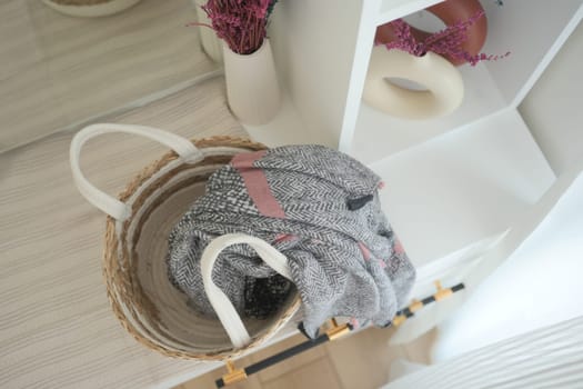 A soft scarf rests casually on a natural basket near a shelf.