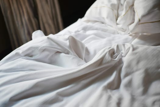 A bed with soft, crumpled white linens creates a serene atmosphere.