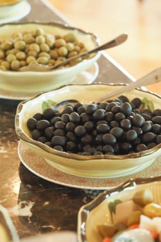 A variety of olives arranged in bowls at a restaurant buffet table.