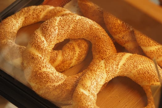 Warm, golden bread with sesame seeds rests in a wooden display case.