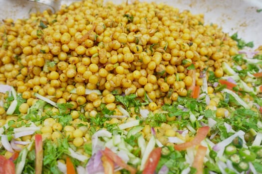 A vibrant bowl of spiced yellow peas alongside fresh vegetables and herbs.