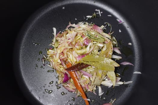Chopped onions, herbs, and spices in a cooking pan .