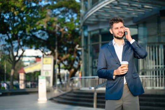 Bearded businessman talking on mobile phone outside office building.