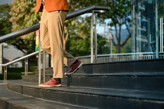 Close up shot of businessman in trendy red sneakers walks down stairs.
