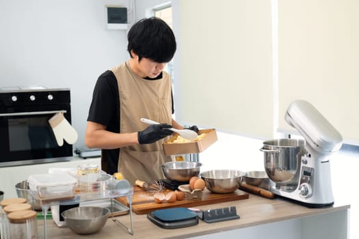 Young baker wearing gloves preparing ingredients for cookie dough.
