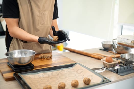 Young entrepreneur preparing homemade chocolate chip cookies in modern kitchen.