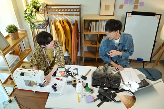 Two designers discussing ideas for a clothing project in a creative studio.