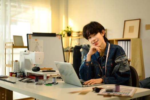 Cheerful young fashion designer working in a creative studio.