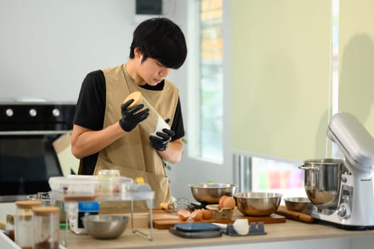 Young baker wearing gloves preparing ingredients for cookie dough.
