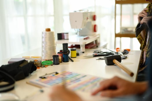 Creative workspace filled with sewing tools, colorful thread spools and fabric swatches.
