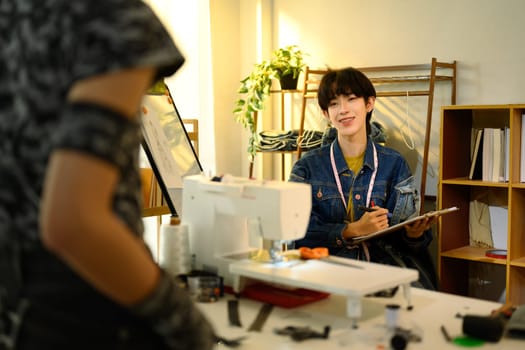 Two designers discussing ideas for a clothing project in a creative studio.