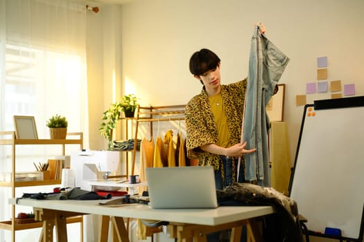 Creative fashion designer inspecting a pair of denim jeans in a creative studio.