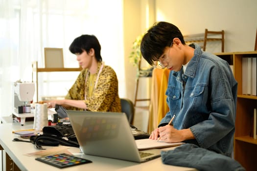 Two young designers brainstorming ideas while working on denim collection.