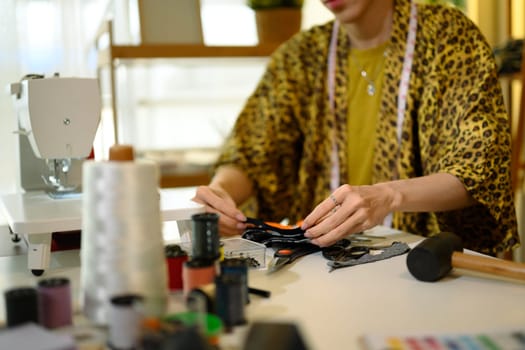 Cropped shot of young fashion designer examining fabric at creative workplace.