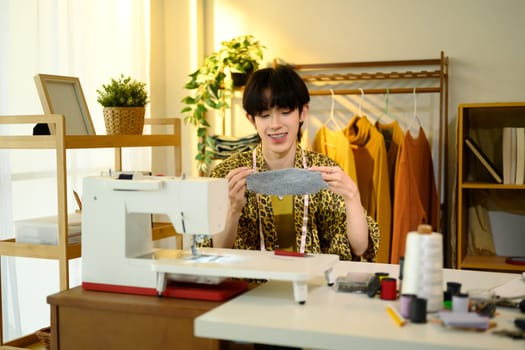 Smiling young fashion designer examining fabric in studio.