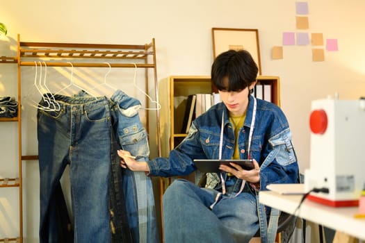 Young small business entrepreneur checking order on digital tablet tablet in a creative workspace.