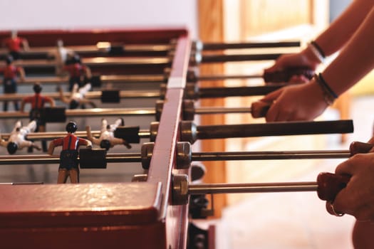 Two hands actively participating in a lively foosball game, showcasing the excitement and competitive spirit of this popular table sport with vibrant player figurines.