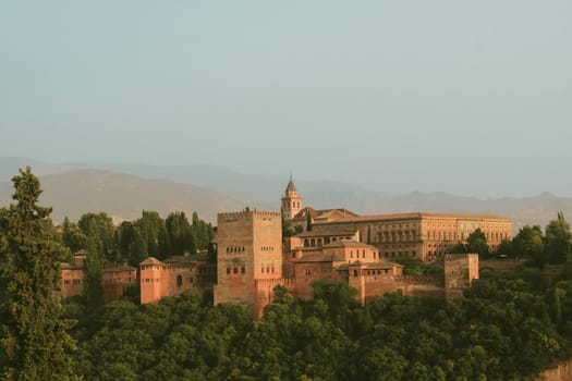 The stunning Alhambra Palace rises above lush greenery, showcasing its historical architecture and beautiful landscape against a serene sky, a true marvel of art and history.