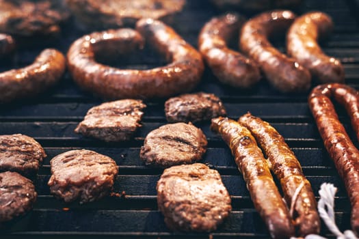 A vibrant assortment of sausages and beef patties being grilled to perfection, showcasing a delicious outdoor cooking experience in a summer setting.