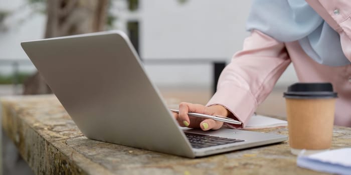A close up of a Muslim woman hand interacting with a laptop, emphasizing her engagement and attention to detail in her work.