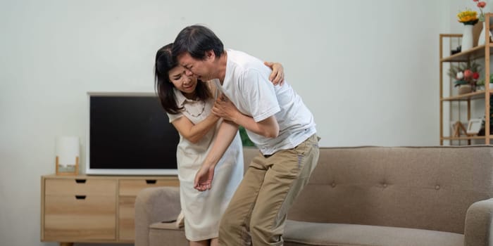 An elderly couple shares a moment of concern as one supports the other during a health issue at home.