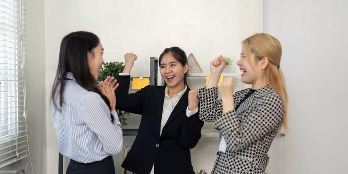 A diverse team of businesswomen expresses excitement and enthusiasm while celebrating their achievements in a modern office.