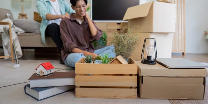 A gay couple unpacks boxes in their new home, emphasizing their teamwork and affectionate bond.