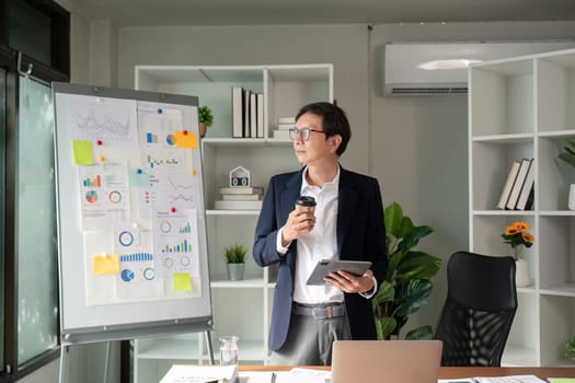 An elderly professional sips coffee while analyzing financial charts, representing a blend of relaxation and focus in the workplace.
