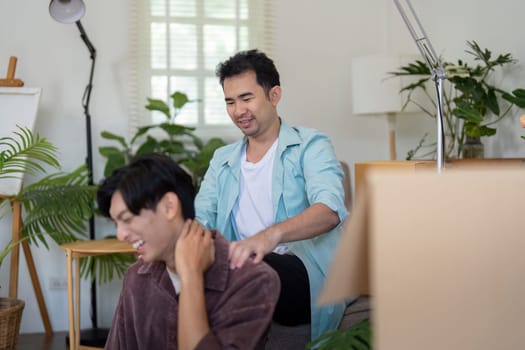 A gay couple shares a laugh while giving each other a massage, enjoying their time together as they settle into their new home.