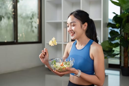 A cheerful woman holds a vibrant salad bowl, celebrating healthy eating and nutrition in a lively indoor space.